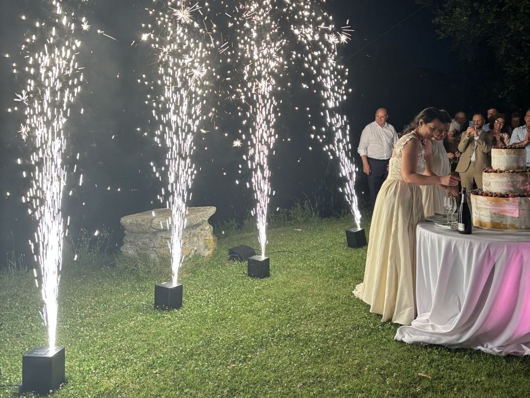 Fontane fredde luminose accese durante il taglio della torta di un matrimonio, con gli sposi e gli invitati