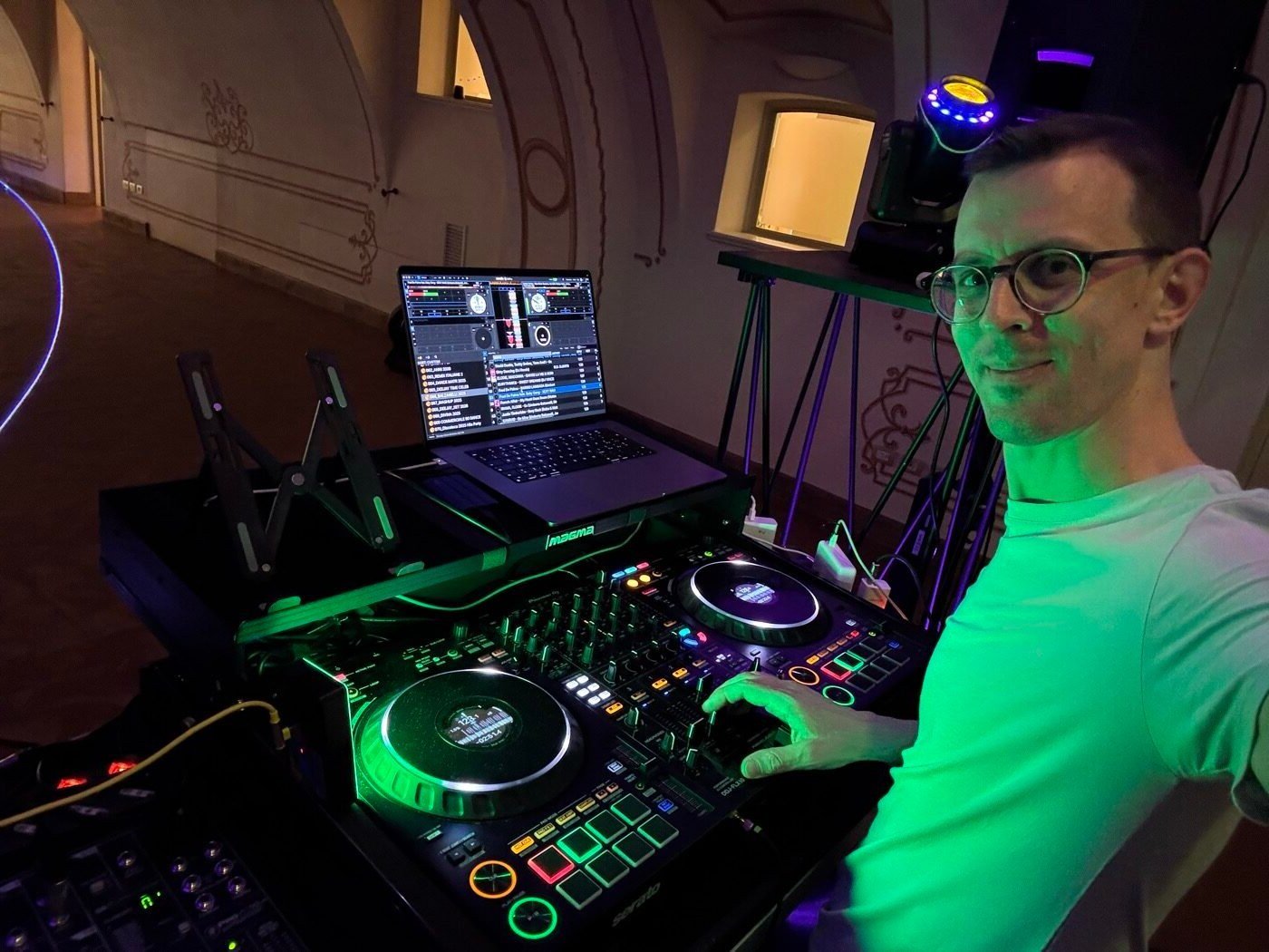 MACO DJ al lavoro in consolle con controller e laptop durante una festa in una sala storica a Bergamo
