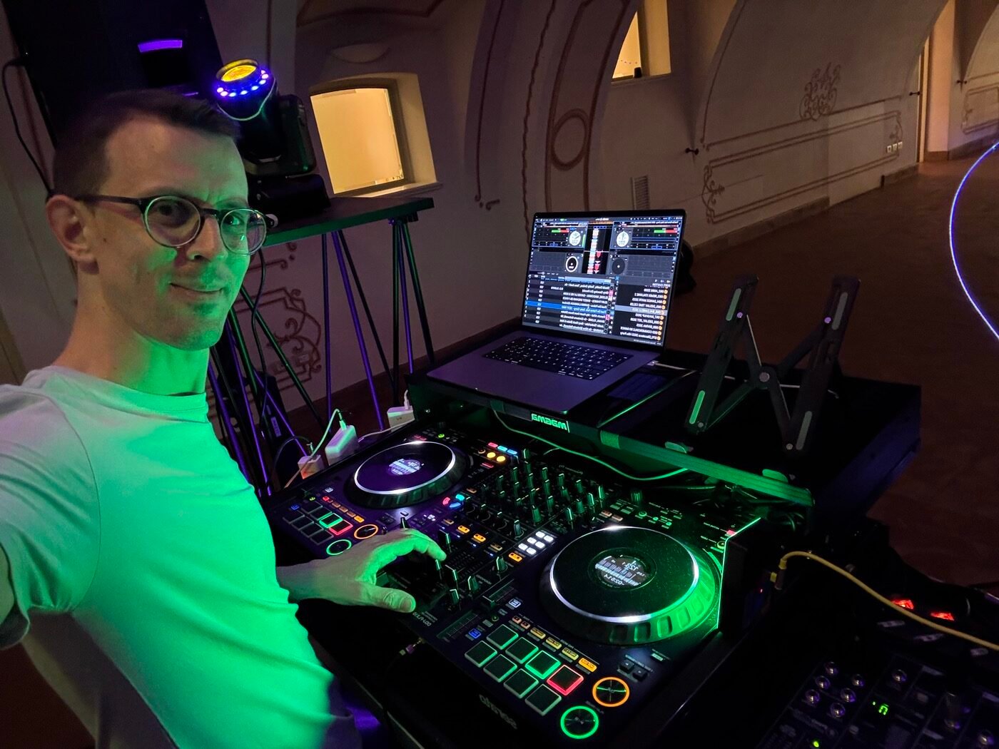 MACO DJ al lavoro in consolle con controller e laptop durante una festa in una sala storica a Bergamo